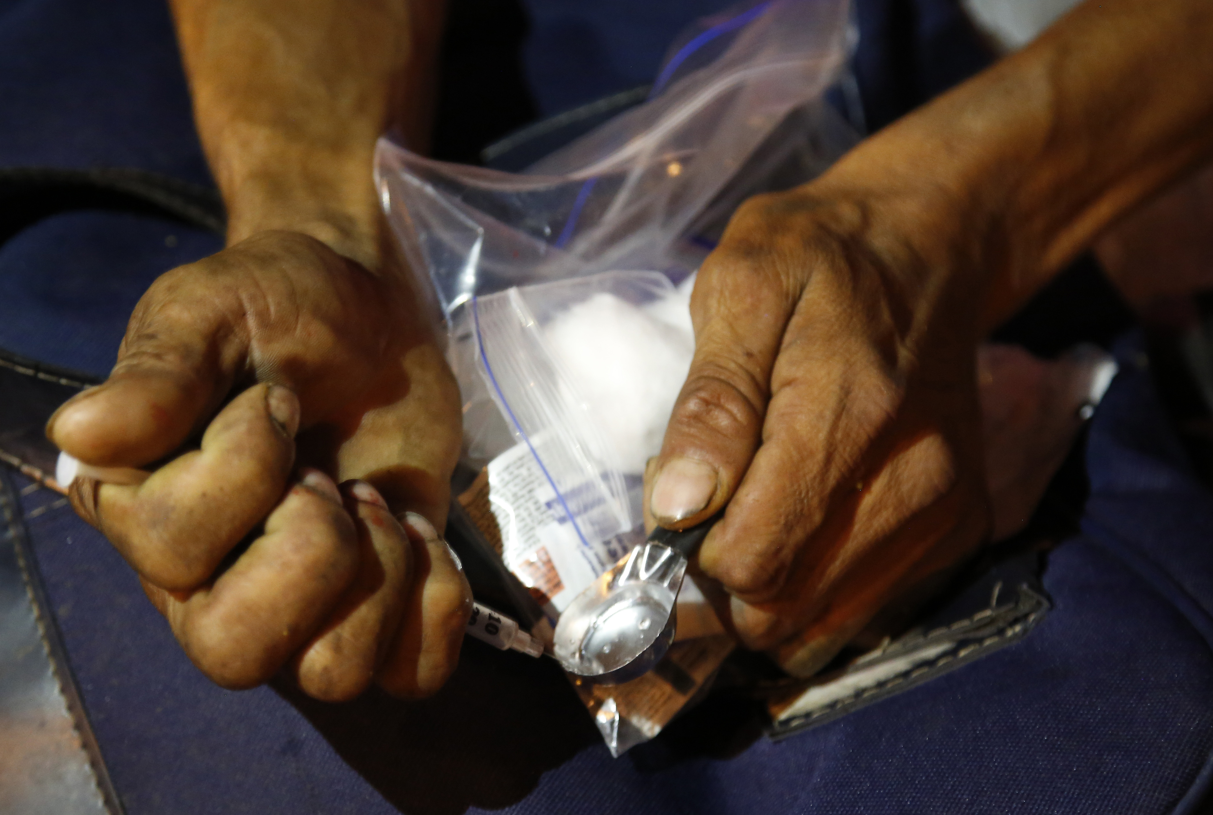 An addict prepares shoot up heroin after receiving a kit including a spoon, a rubber tube, cotton, sterilized water and clean syringes distributed by a program sponsored by the Open Society Foundation and government agencies in Dosquebradas, Colombia. (AP/Fernando Vergara)