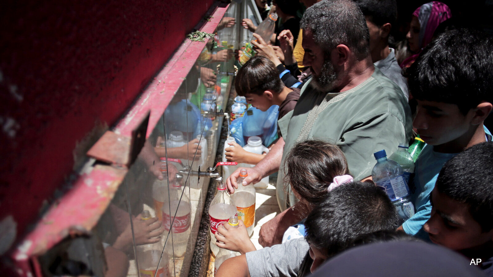 Palestinians fill empty bottles of water at the New Gaza Boys United Nations School. Israel controls access to Palestinian aquifers, and has been restricting access to local residents.