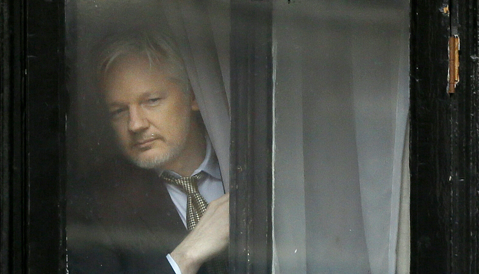 Wikileaks founder Julian Assange appears at the window before speaking on the balcony of the Ecuadorean Embassy in London, Friday, Feb. 5, 2016.
