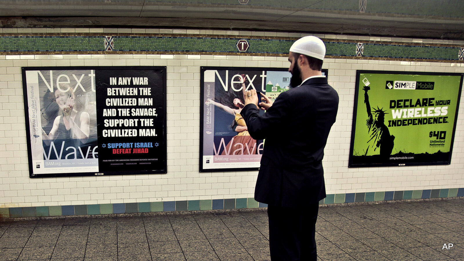 Cyrus McGoldrick, takes a photo with his cell phone of an anti-Muslim poster in New York's Times Square subway station.