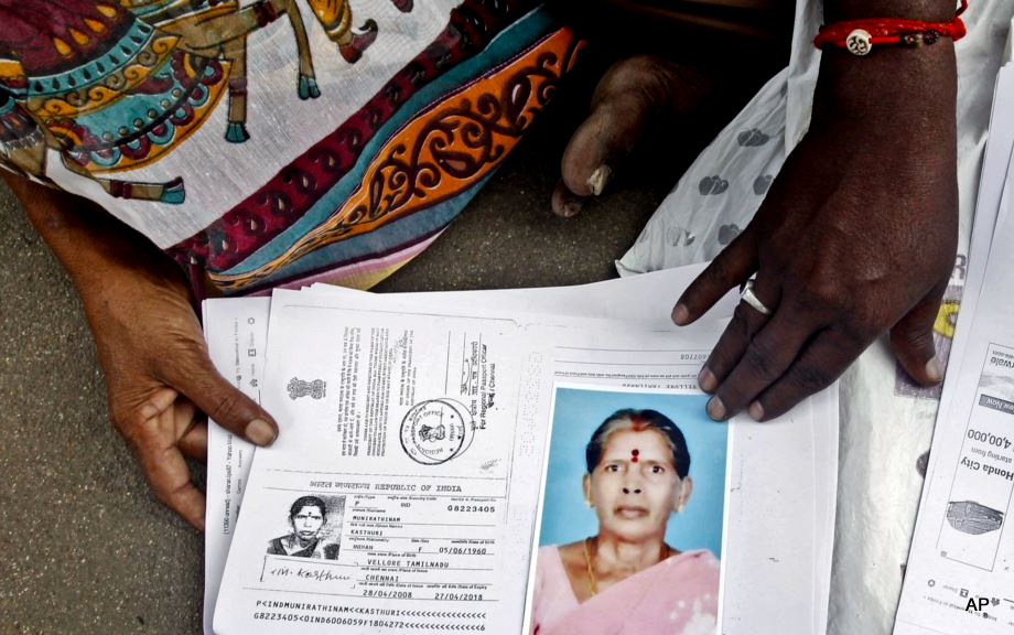 Relatives of Kasthuri Munirathinam, an Indian woman who lost an arm during an escape attempt from her Saudi employer. display a photo of her and copies of her employment documents, in Chennai, India, Oct. 24, 2015.