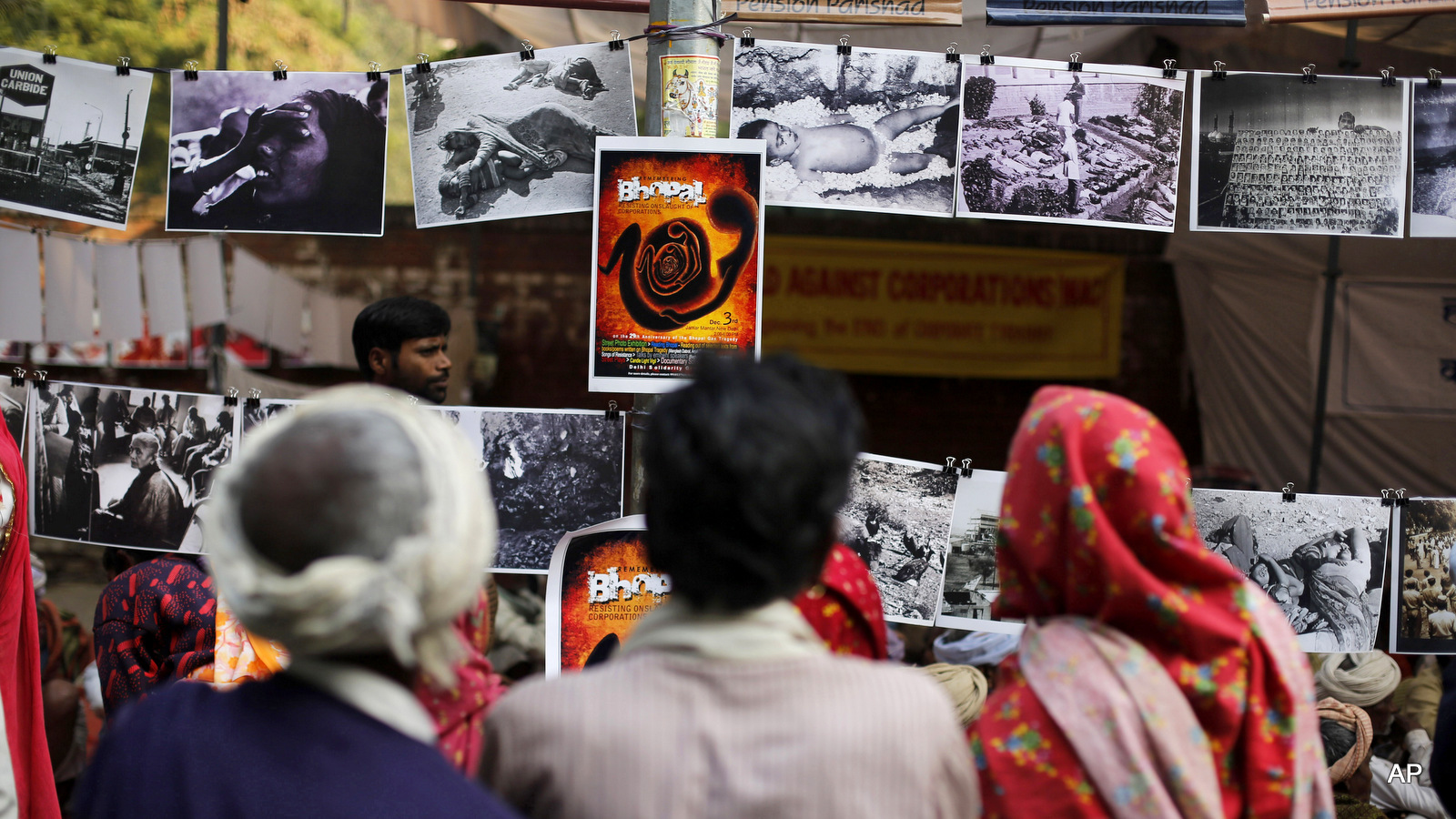 Survivors and their supporters look at photographs of the Bhopal gas disaster displayed during a protest on the anniversary of the tragedy near the Indian parliament in New Delhi, India, Tuesday, Dec. 3, 2013. On this day in 1984, thousands of people died after a cloud of methyl isocyanate gas escaped from a pesticide plant operated by a Union Carbide subsidiary in Bhopal in central India.