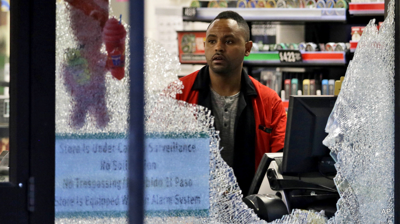 A clerk looks at broke windows shot out at a store in downtown Dallas, Friday, July 8, 2016.  Snipers opened fire on police officers in the heart of Dallas during protests over two recent fatal police shootings of black men.