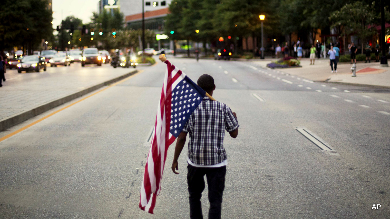 Skylar Barrett walks with an American flag in the middle of the street during a march through the Buckhead neighborhood against the recent police shootings of African-Americans on Monday, July 11, 2016, in Atlanta.