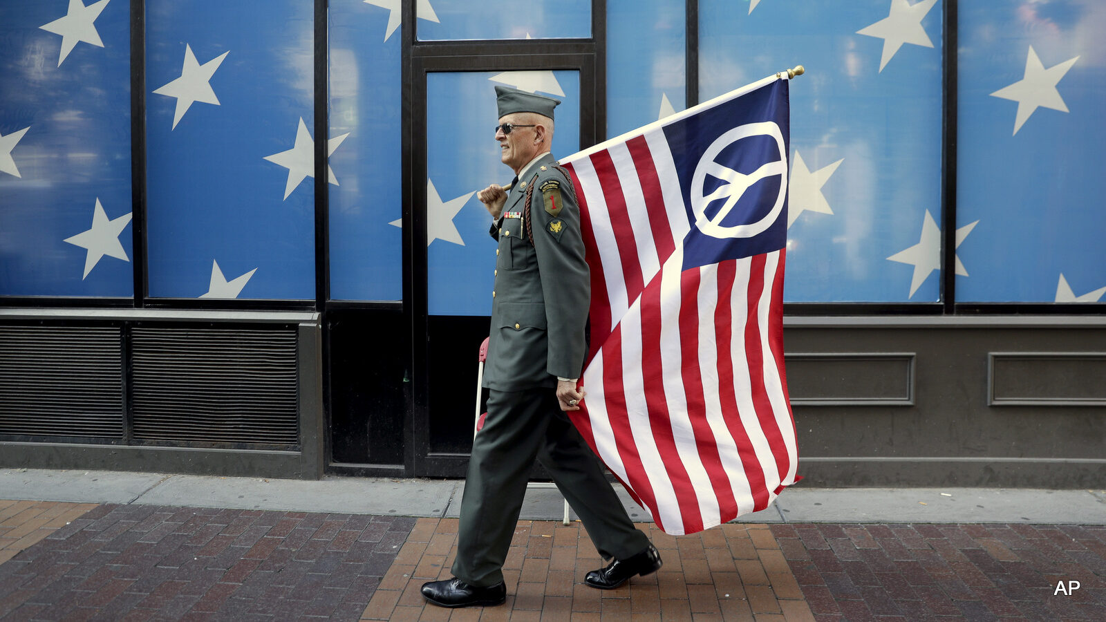 A protester carrying a peace flag walks in downtown Cleveland, Sunday, July 17, 2016, in preparation for the Republican National Convention that starts Monday.