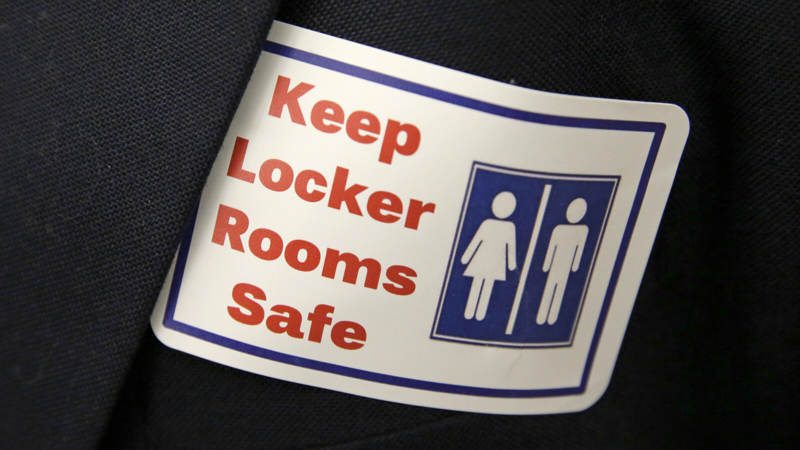 A sticker that reads, "Keep Locker Rooms Safe," is worn by a person supporting a bill that would eliminate Washington's new rule allowing transgender people use gender-segregated bathrooms and locker rooms in public buildings consistent with their gender identity, Wednesday, Jan. 27, 2016, outside a Washington Senate hearing room at the Capitol in Olympia, Wash.