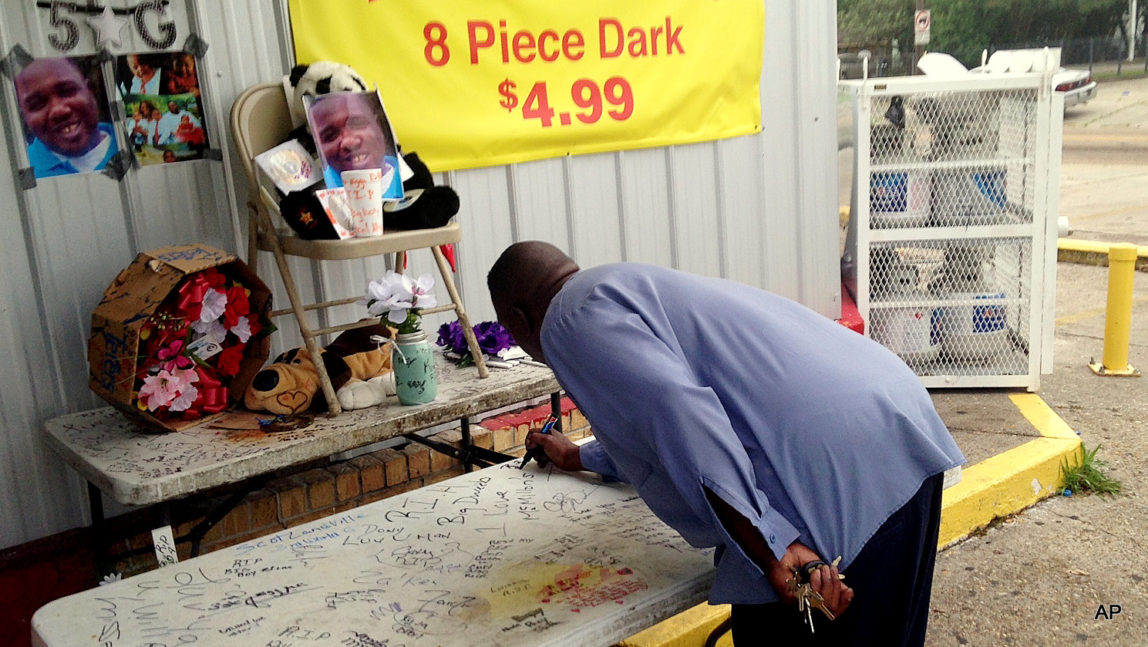 Arthur Baines signs "RIP Big Dogg" on a folding table that Alton Sterling used to sell homemade music CDs outside the convenience store, Wednesday, July 6, 2016, in Baton Rouge, La.