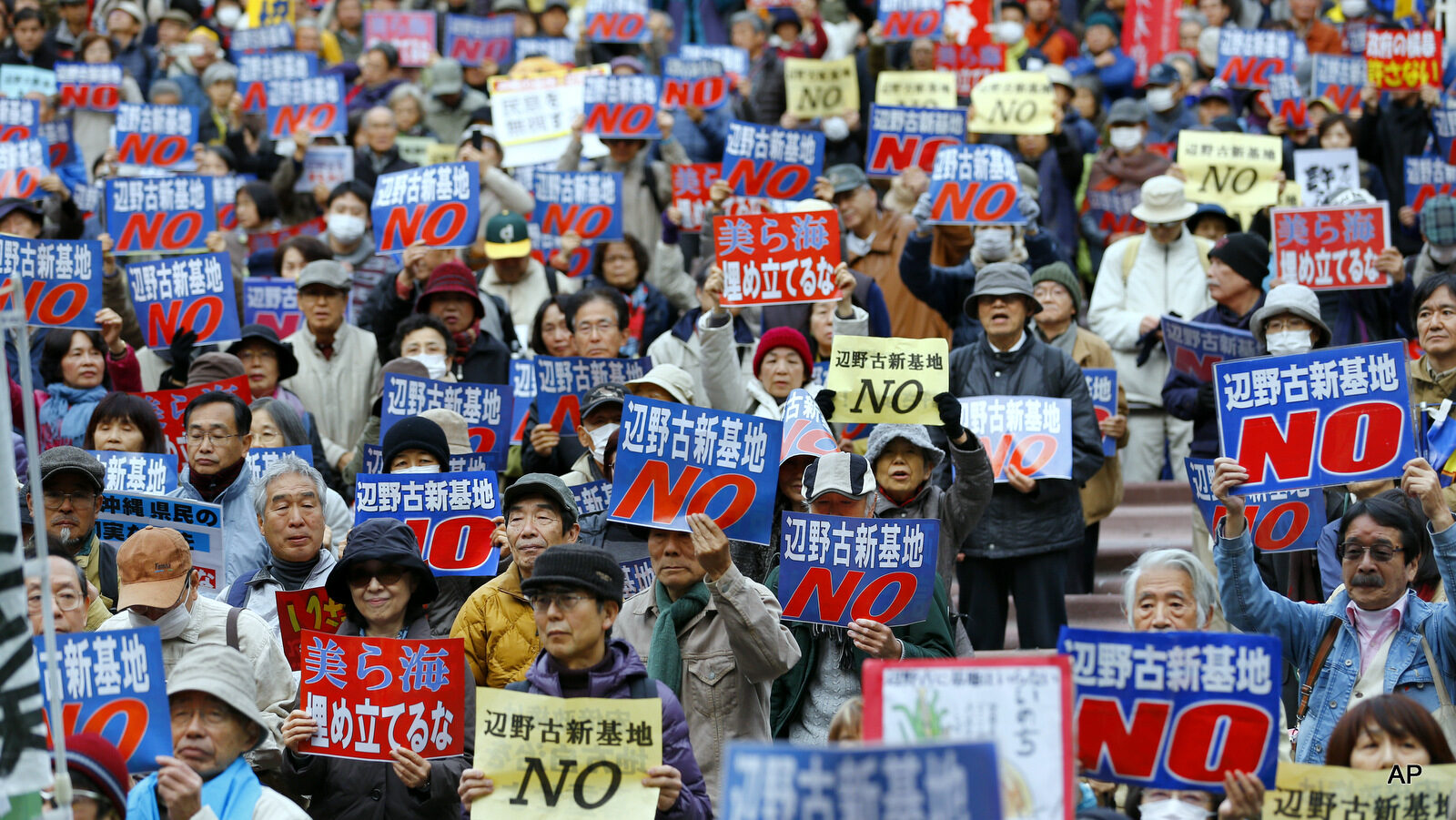 Protesters hold placards with a slogan that reads: "No to Henoko new base" during a rally in Tokyo as they show their strong support to Okinawans after the Japanese government took the local government in Okinawa to court in mid-November, launching a legal battle in their longstanding dispute over the planned relocation of a U.S. military air base on the southern island.