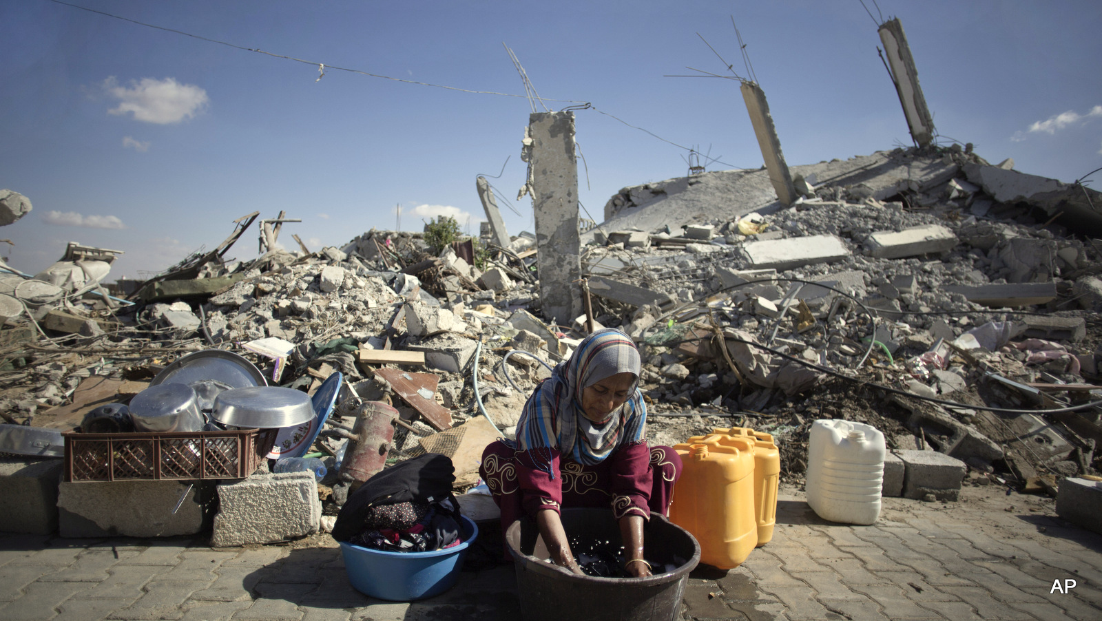 A woman washes clothes as she sits in front of the rubble of her family house in Khuzaa, southern of Gaza Strip.