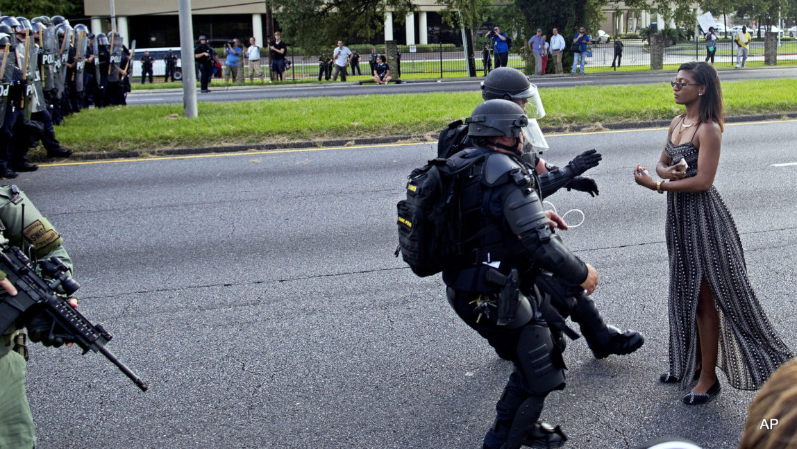 A protester is grabbed by police officers in riot gear after she refused to leave the motor way in front of the the Baton Rouge Police Department Headquarters in Baton Rouge, La. Police made nearly 200 arrests in Louisiana's capital city during weekend protests around the country in which people angry over police killings of young black men sought to block some major interstates.