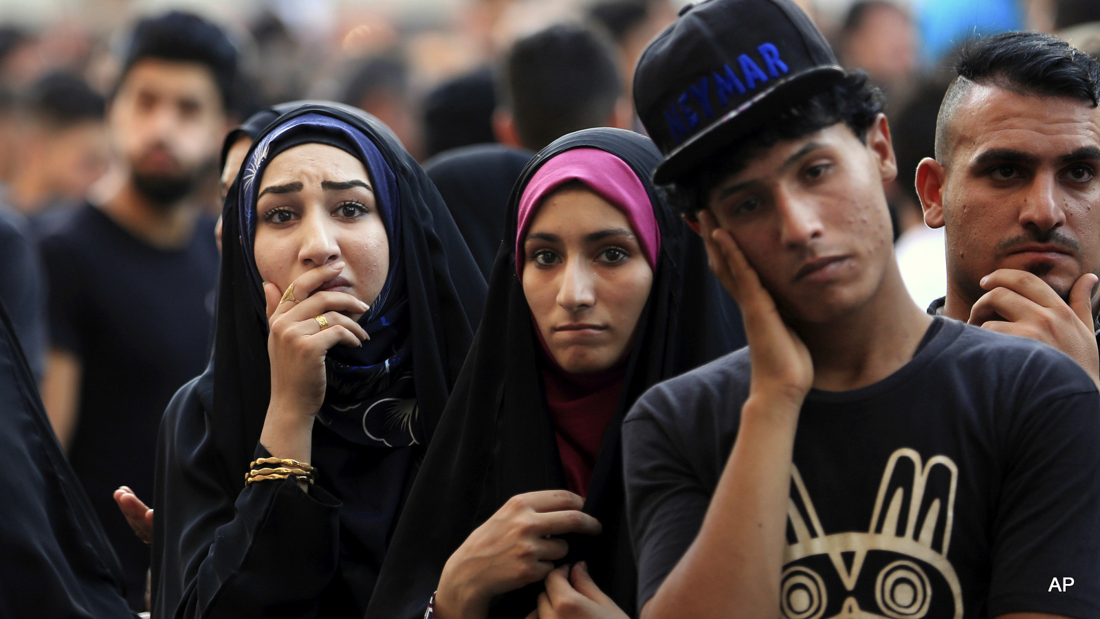 People wait for family members who went missing as paramedics look for burned bodies inside a mall at the scene of Sunday's massive truck bomb attack claimed by ISIS in the Karada neighborhood, Baghdad, Iraq, Thursday, July 7, 2016. 