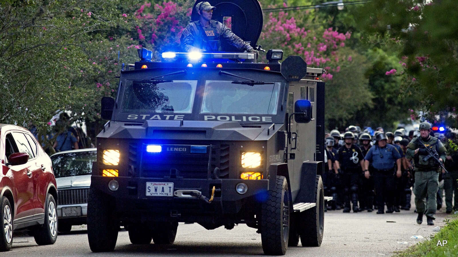 An armored police truck leads a troop of police through a residential neighborhood in Baton Rouge, La. on Sunday, July 10, 2016.