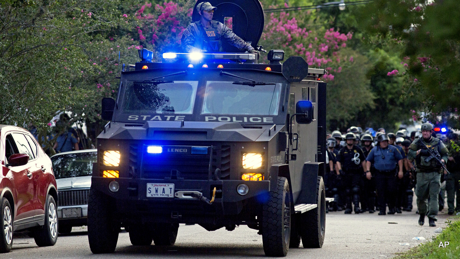 An armored police truck leads a troop of police through a residential neighborhood in Baton Rouge, La. on Sunday, July 10, 2016. 