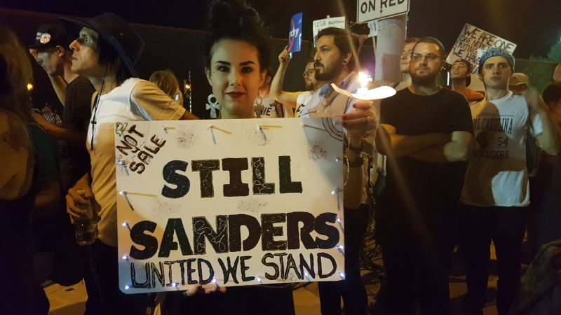 An activist holds a “Still Sanders” sign during a candlelit vigil outside the Wells Fargo Center in Philadelphia, site of the 2016 Democratic National Convention, July 27, 2016. (MintPress News / Kit O’Connell)