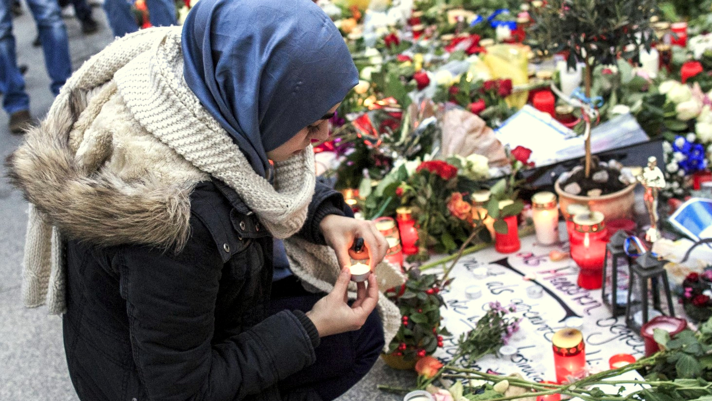 A young woman lights a candle outside the French Embassy in Berlin.