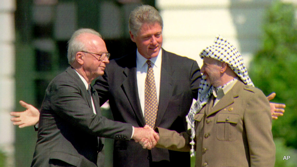 President Clinton gestures as Israeli Prime Minister Yitzhak Rabin, left, and Palestine Liberation Organization Chairman Yasser Arafat shake hands after signing a peace accord, Monday September 13, 1993 on the South Lawn of the White House.