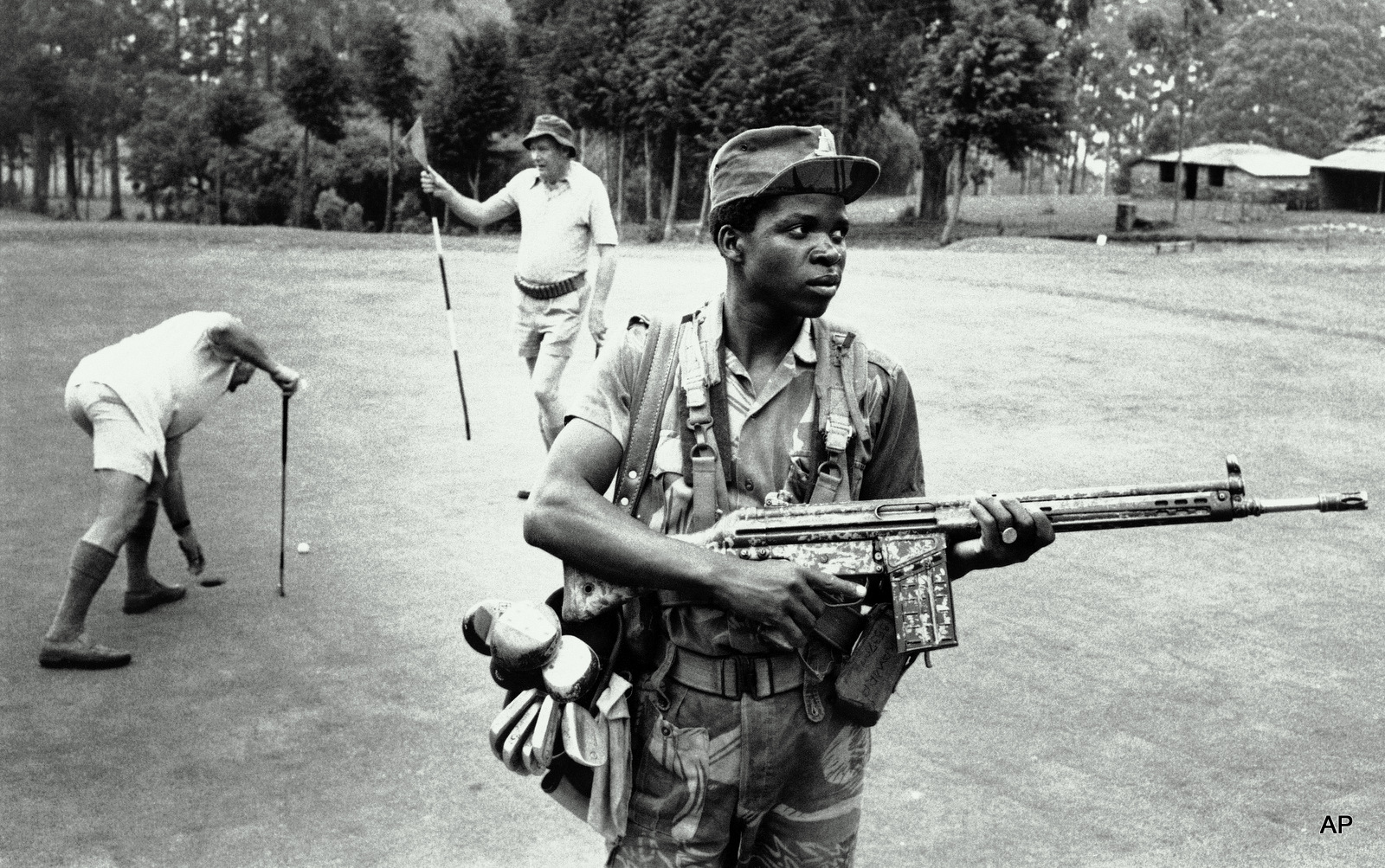 An armed private guard provides both service and security to white golfers at a golf course at the Hotel Leopard 1978 in Rhodesia. 