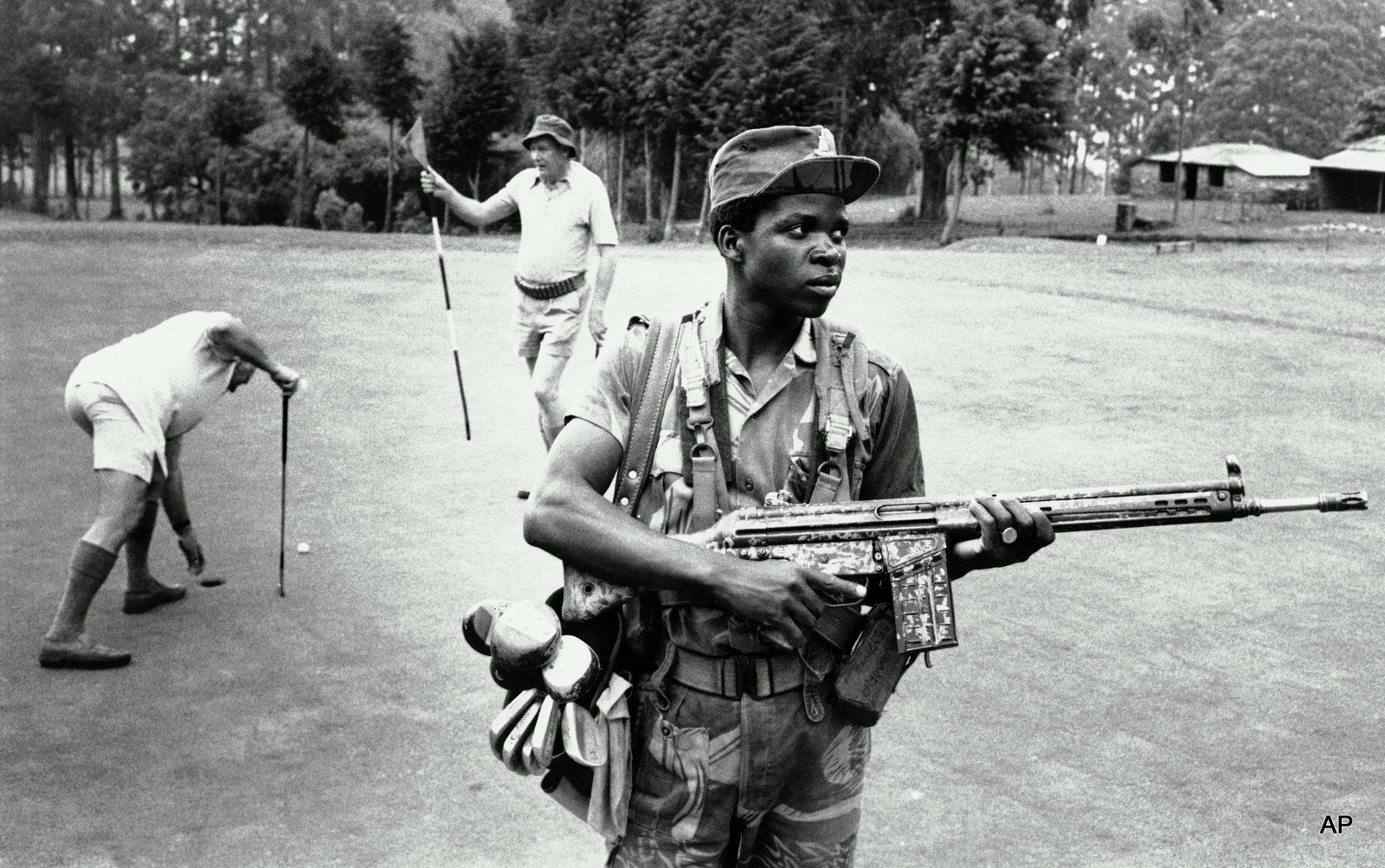 An armed private guard provides both service and security to white golfers at a golf course at the Hotel Leopard 1978 in Rhodesia.