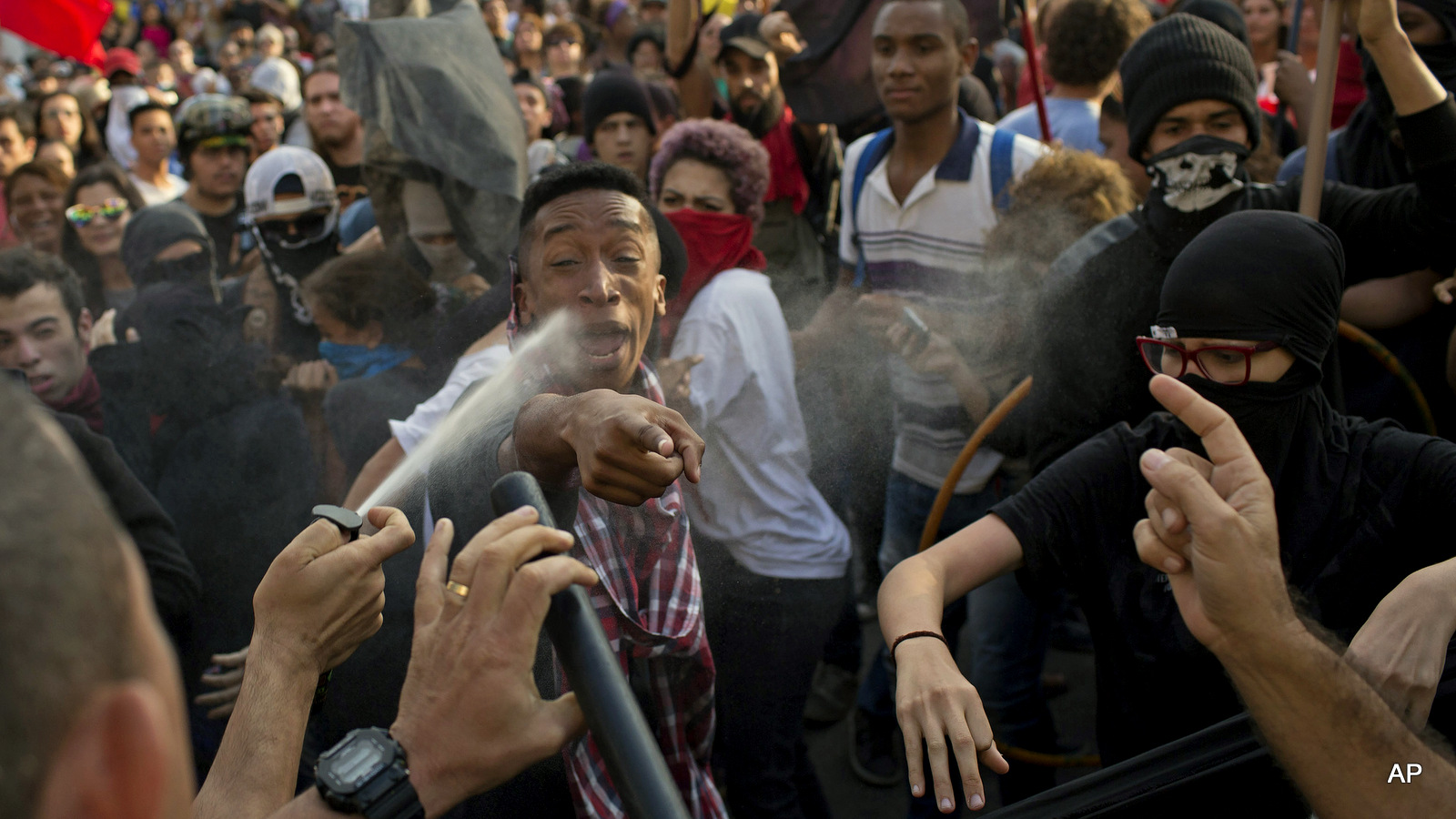 A police officer pepper sprays demonstrators as a scuffle breaks out during a protest against the money spent on Rio's 2016 Summer Olympics on the route of the Olympic torch, in Niteroi, Brazil, Tuesday, Aug. 2, 2016. The three-month torch relay across Brazil will end at the opening ceremony on Aug. 5, in Rio de Janeiro's Maracana Stadium.