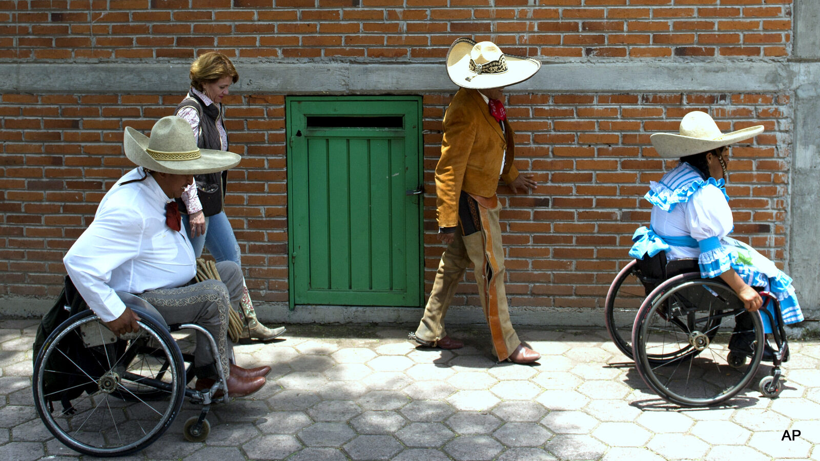 In this July 10, 2016 photo, accompanied by Mexican cowboy and team captain Juan Manuel Garcia, Salvador Espinoza and his wife Graciela Sanchez Martinez wheel themselves to a staging area at a Mexican rodeo arena in Cuautitlán Izcalli, Mexico. “It is a sensation that you can’t explain,” said Garcia, who survived a stroke and seven-month coma that left him with muscular weakness on the right side of his body, total loss of mobility in his right leg and three amputated fingers. “Now it is gratifying, now it is something motivating, to know that I can dominate any animal.”