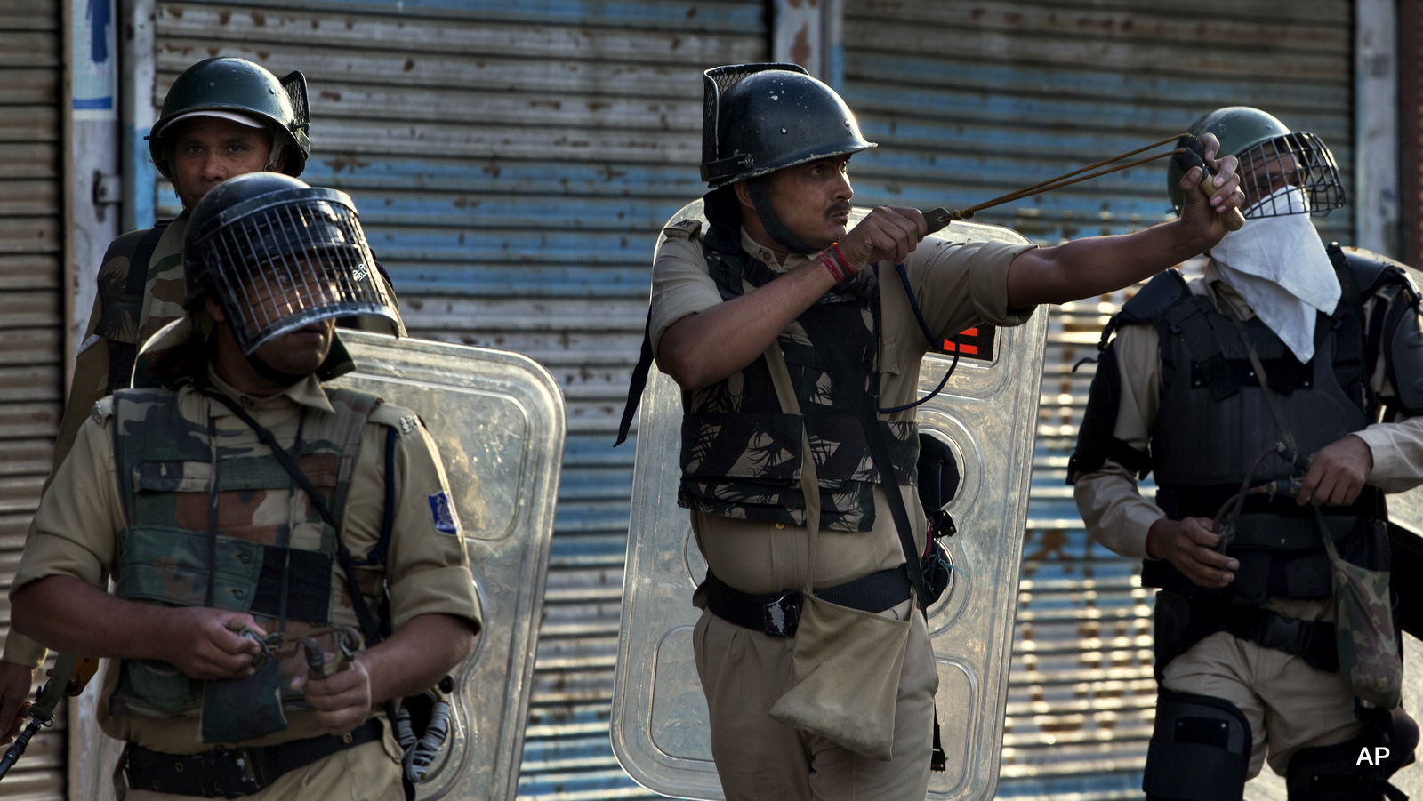 An Indian paramilitary soldier uses a sling to shoot glass marbles at Kashmiri protesters after a day long curfew in Srinagar, Kashmir. Aug. 7, 2016. (AP Photo)