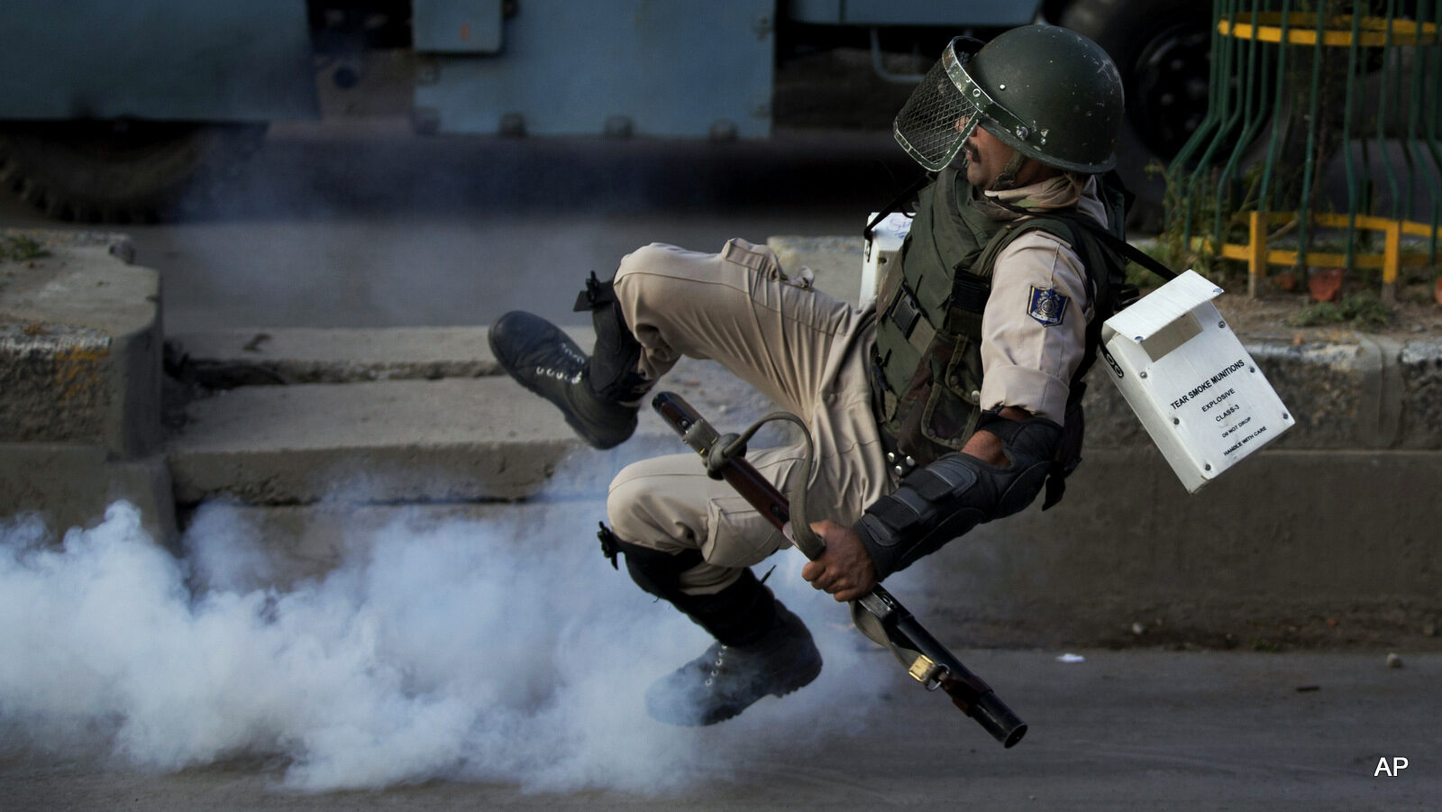 An Indian paramilitary soldier falls down as he tries to kick back an exploded tear gas shell thrown back at them by Kashmiri protesters at the end of a day long curfew in Srinagar, Indian occupied Kashmir, Monday, Aug. 8, 2016.