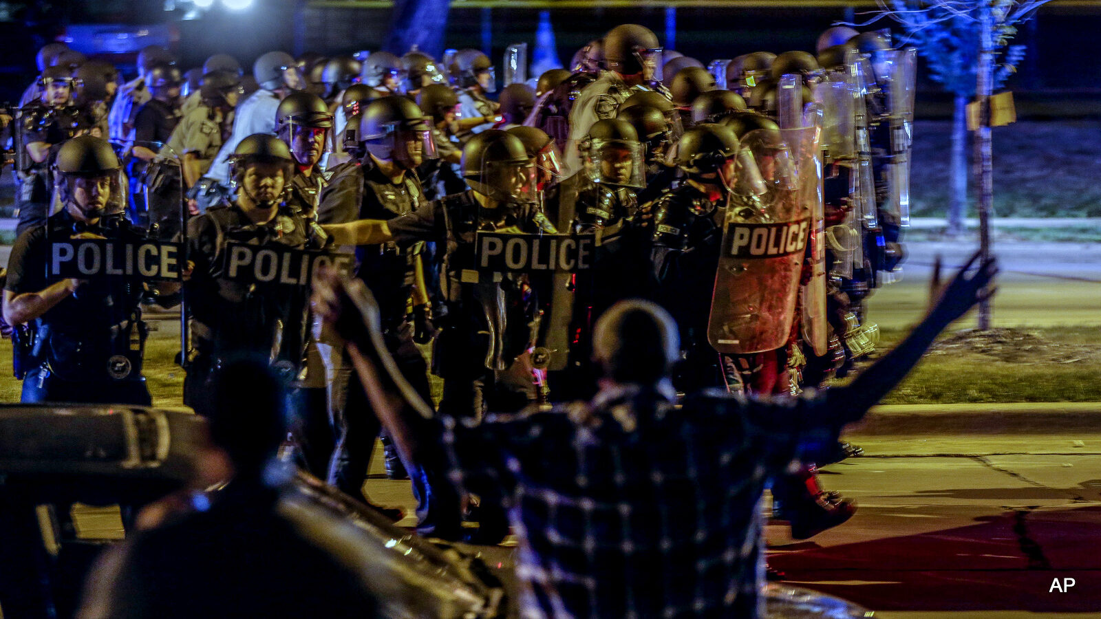 Police move in on a group of protesters throwing rocks at them in Milwaukee, Sunday, Aug. 14, 2016. Police said one person was shot at a Milwaukee protest on Sunday evening and officers used an armored vehicle to retrieve the injured victim during a second night of unrest over the police shooting of a black man.
