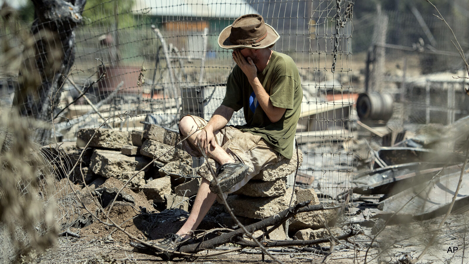 James McCauley weeps as he views the burned out remains of his home in Lower Lake, Calif., Monday, Aug. 15, 2016. McCauley traversed a creek by boat and foot for a half mile to see the property.