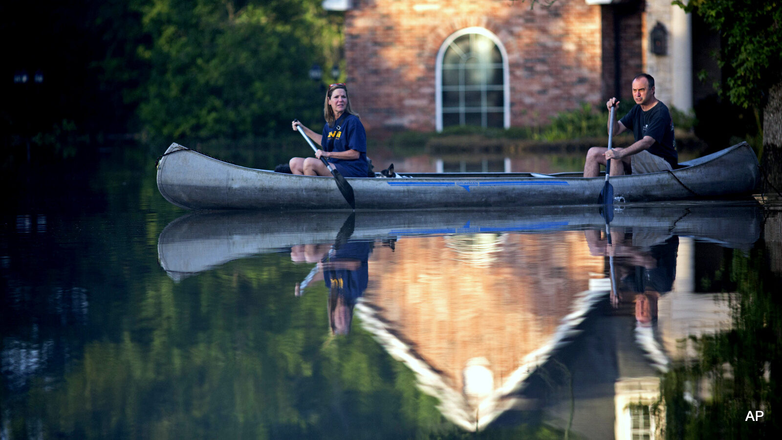 Danny and Alys Messenger canoe away from their flooded home after reviewing the damage in Prairieville, La., Tuesday, Aug. 16, 2016.