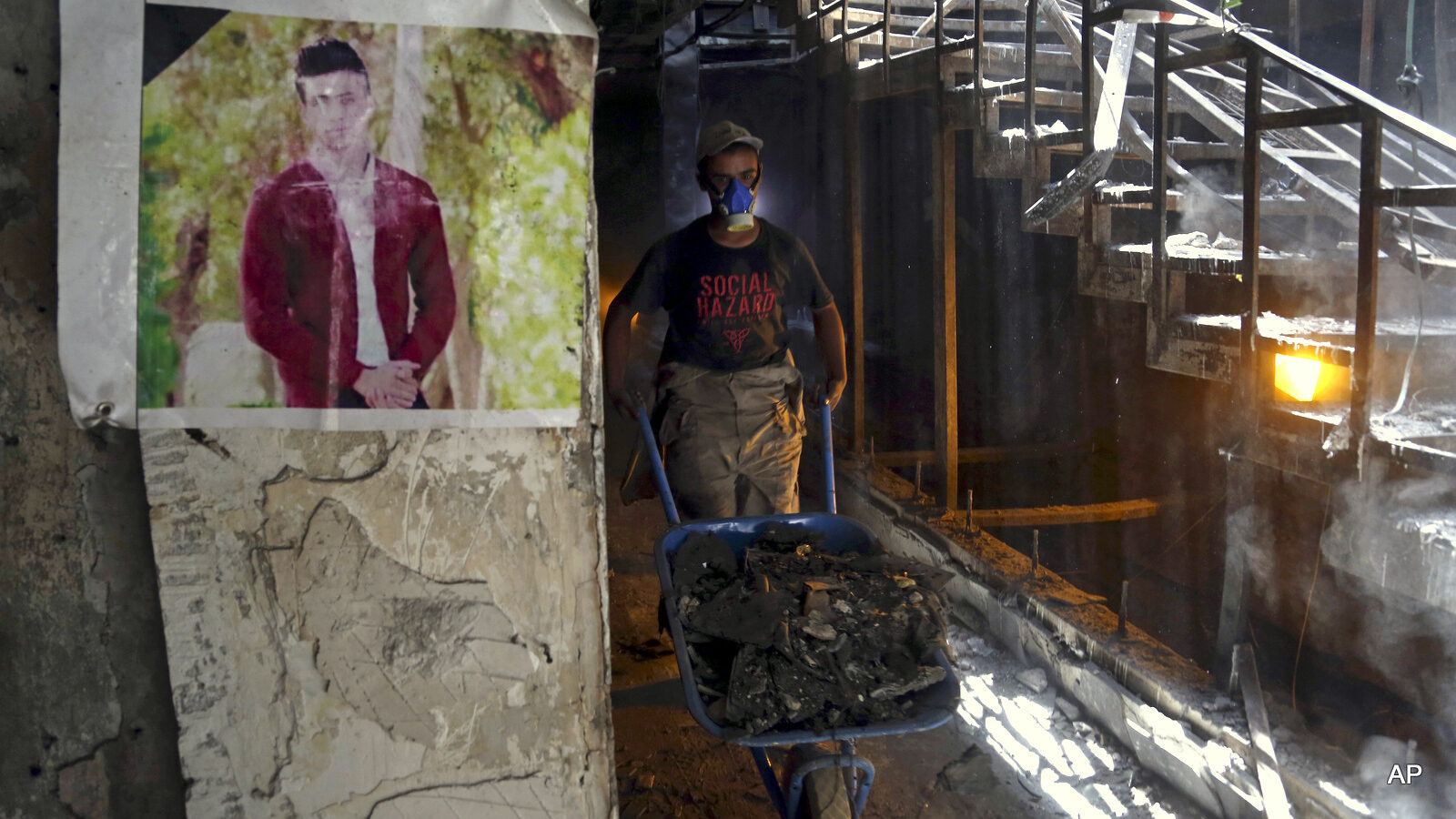 A municipal worker passes by a poster of a bomb victim during the cleaning process at the site of a deadly Islamic State group-claimed mall bombing in the Karradah neighborhood of central Baghdad, Iraq, Sunday, Aug. 21, 2016. The scene of the blast that ultimately claimed the lives of nearly 300 people, according to the ministry of health, sat as a memorial to the dead for weeks after the attack. The July 3 attack was the single deadliest bombing in Baghdad since the 2003 toppling of Saddam Hussein and it fueled anger toward the Iraqi government over the lack of security in the capital.