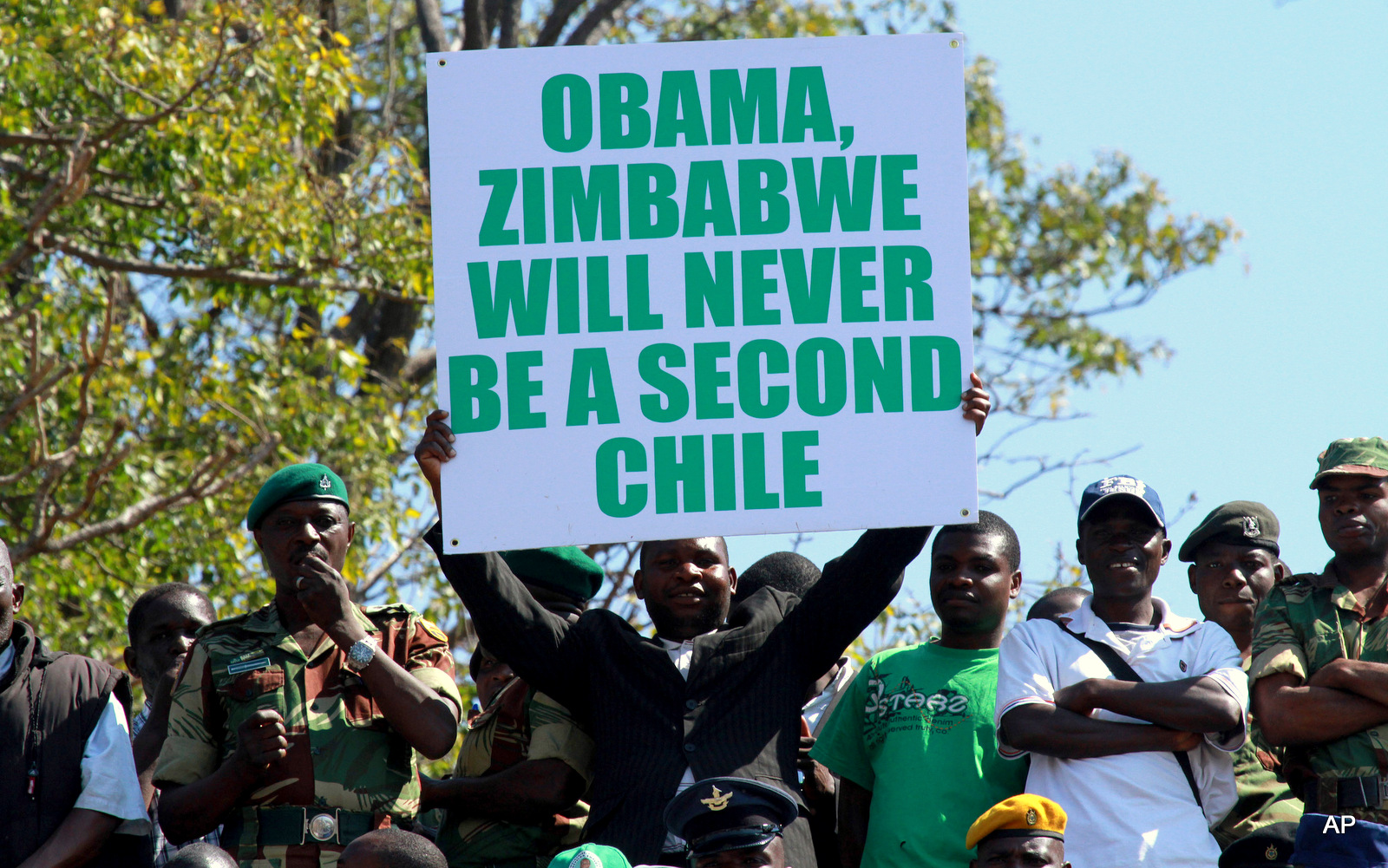A man holds a poster with a message for United States President Barack Obama at Zimbabwe's Commemoration of Heroes day in Harare, Monday, Aug.12, 2013. Zimbabwean President elect Robert Mugabe was the guest speaker at the event. Mugabe recieved more than 60 percent of the vote in recent Presidential elections.