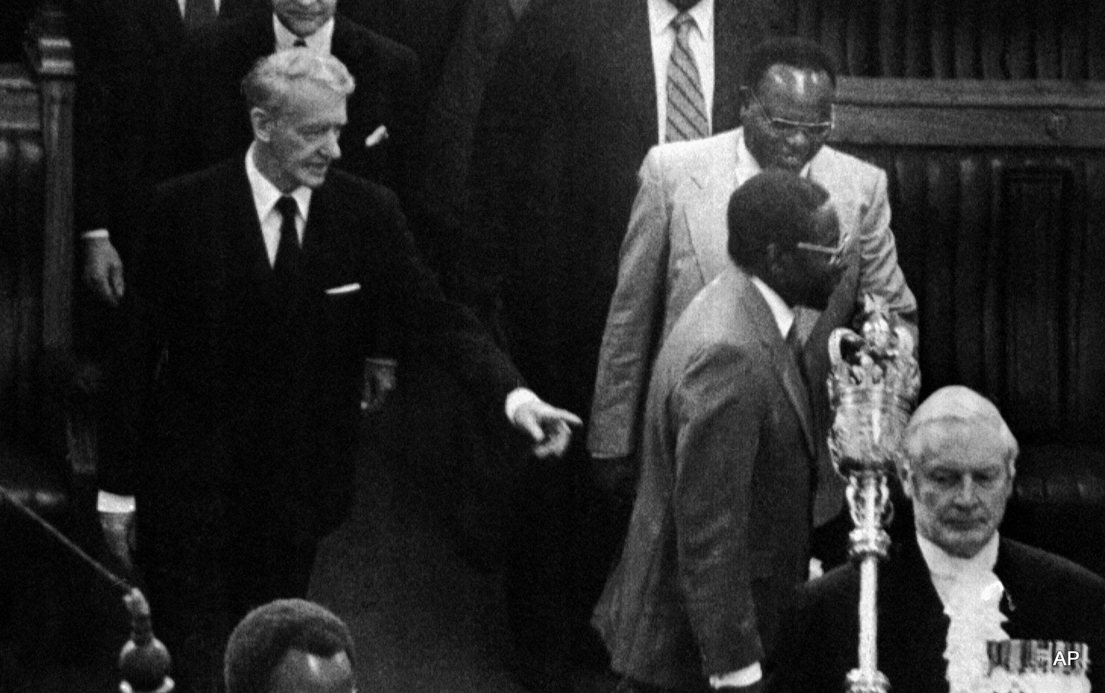 At the opening of first Parliament of independent Zimbabwe, former Premier Ian Smith, points out to newly elected Prime Minister Robert Mugabe the way to the Premier’s seat, in Salisbury, Zimbabwe, on May 14, 1980. Among black Parliamentarians (all Ministers) following Mugabe are Vice Premier Simon Musenda (smiling) and Nationalist Veteran Leader Joshua Nkomo. 