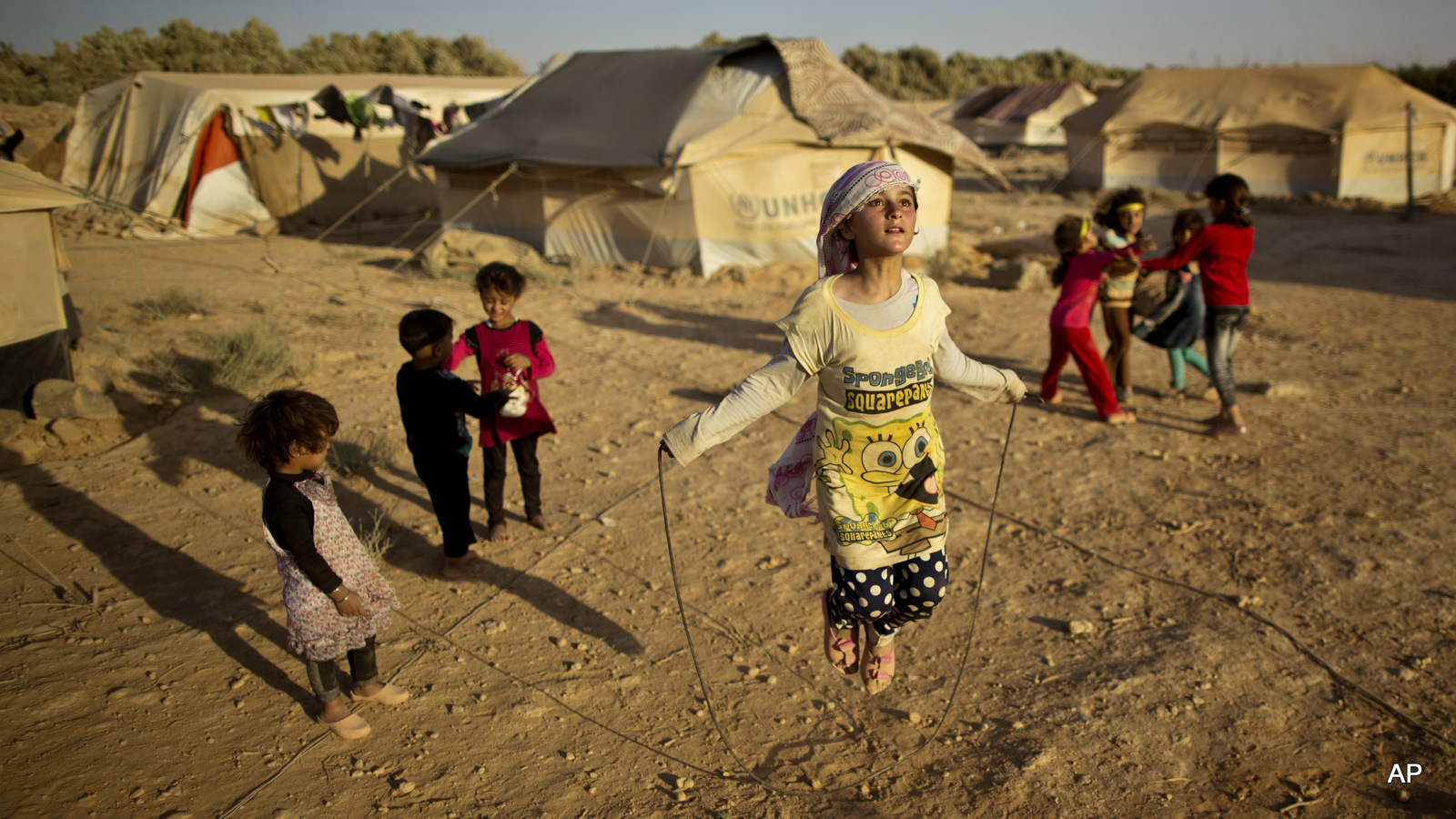 Young refugee girls, skip rope near their tents at an informal tented settlement on the outskirts of Mafraq, Jordan. 