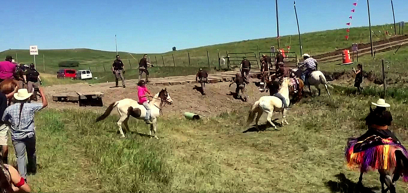 Police guarding the construction of the Dakota access pipeline flee as local Native-American activists confront them on horseback.
