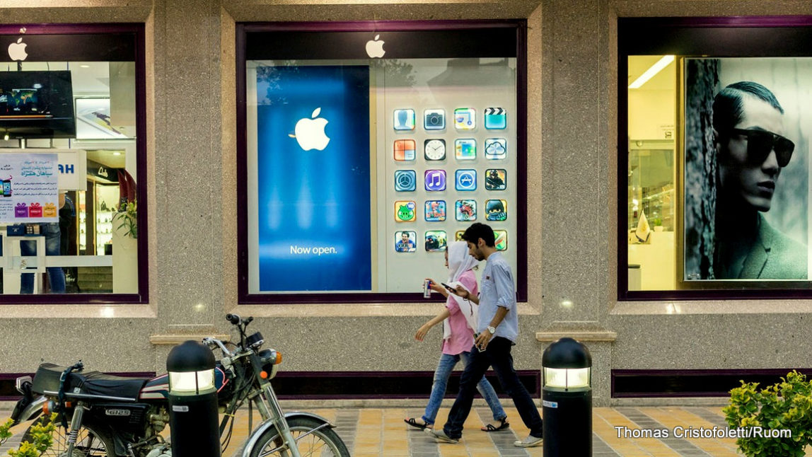 Iranian youth walk in front of a recently opened unofficial Apple reseller.