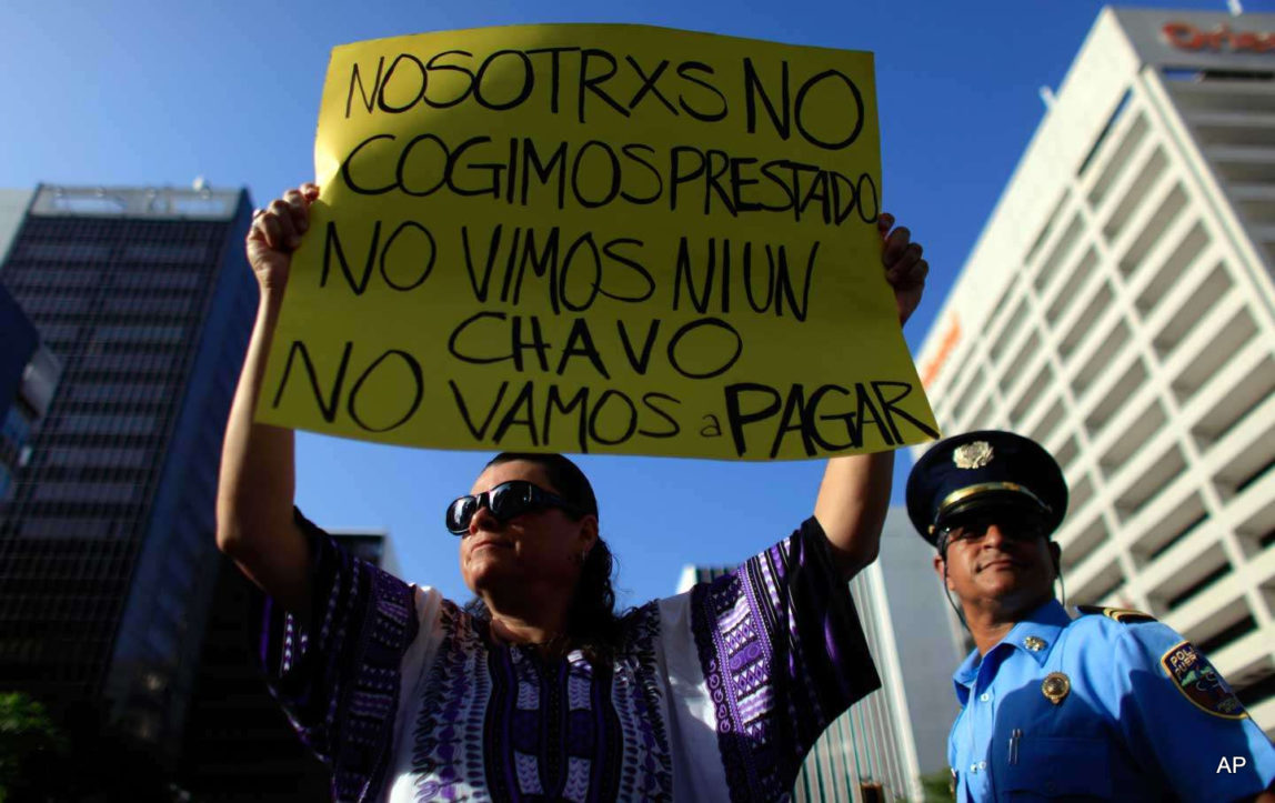 A protester holds a sign that reads in Spanish, “We didn't take out a loan. We didn't see a dime. We're not going to pay” during a protest in San Juan, Puerto Rico, on July 15, 2015.