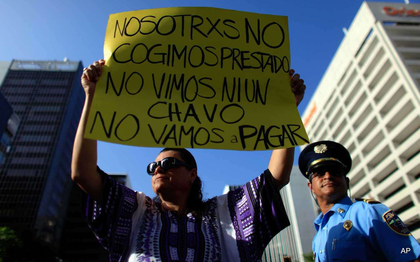 A protester holds a sign that reads in Spanish, “We didn't take out a loan. We didn't see a dime. We're not going to pay” during a protest in San Juan, Puerto Rico, on July 15, 2015.