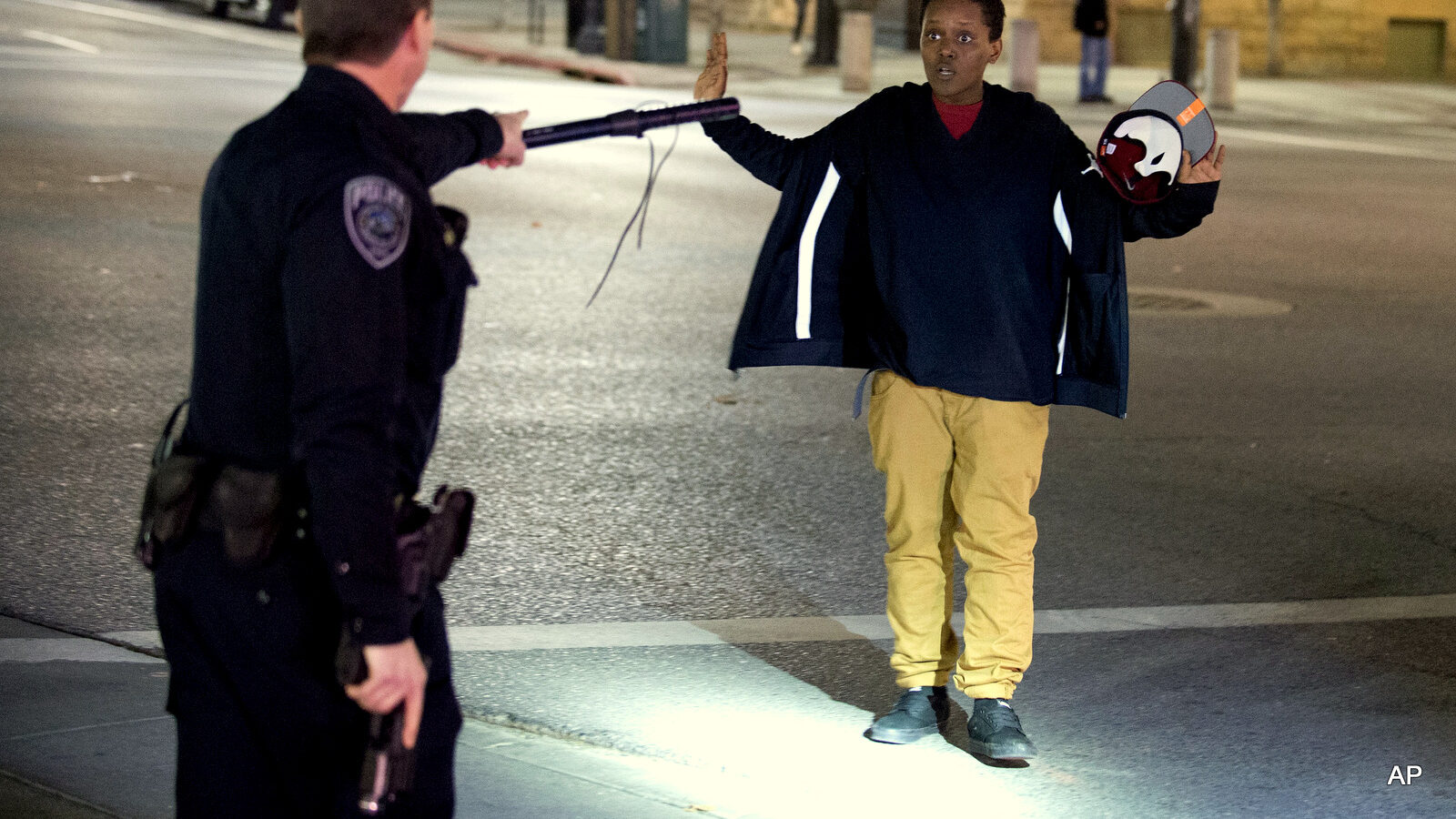 Police stop a person as he walks away from a crowd that formed after an officer-involved shooting at on South Rio Grande Street in Salt Lake City. Salt Lake County District Attorney Sim Gill said officers acted appropriately when they fired at Abdullahi "Abdi" Mohamed because police believed he was about to seriously injure or kill a man with a metal broom handle.