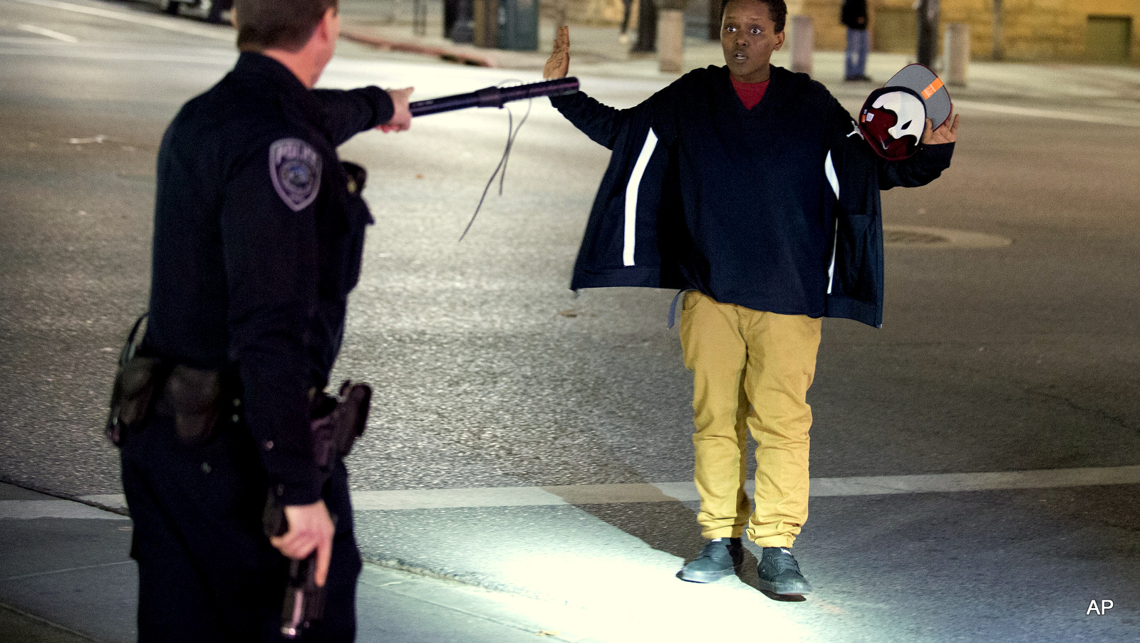 Police stop a person as he walks away from a crowd that formed after an officer-involved shooting at on South Rio Grande Street in Salt Lake City. Salt Lake County District Attorney Sim Gill said officers acted appropriately when they fired at Abdullahi "Abdi" Mohamed because police believed he was about to seriously injure or kill a man with a metal broom handle.