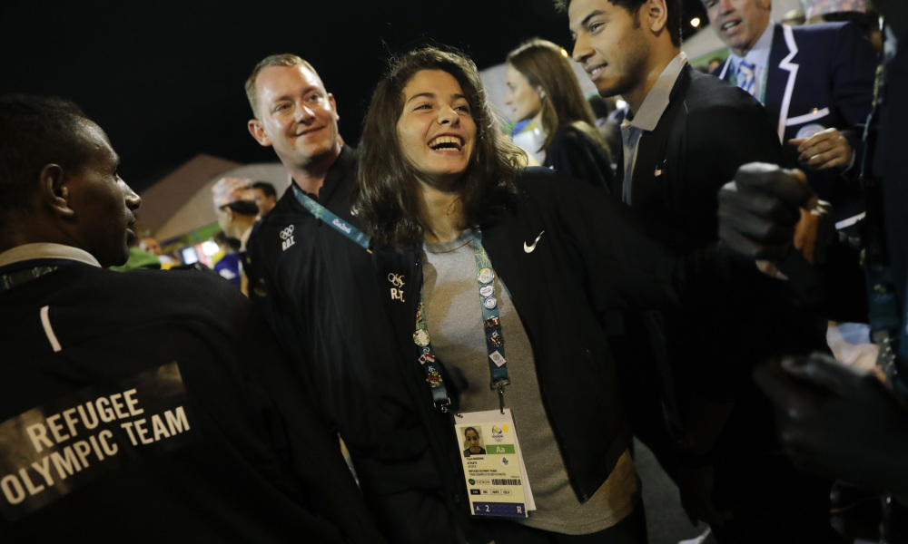 Refugee Olympic Team's Yusra Mardini, center, smiles during a welcome ceremony held at the Olympic village ahead of the 2016 Summer Olympics in Rio de Janeiro, Brazil, Wednesday, Aug. 3, 2016. (AP Photo/Jae C. Hong)