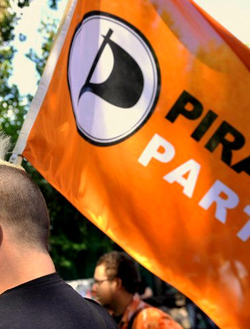 A member of Germany's Pirate Party holds a flag of the party (Credit: AP/Gero Breloer)