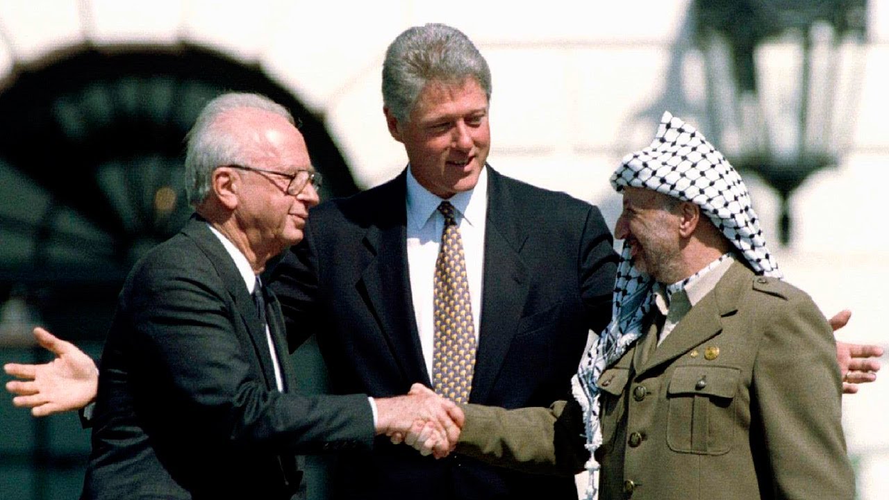 President Clinton gestures as Yitzhak Rabin, left, and Yasser Arafat shake hands Sept. 13, 1993. (Ron Edmonds/AP)