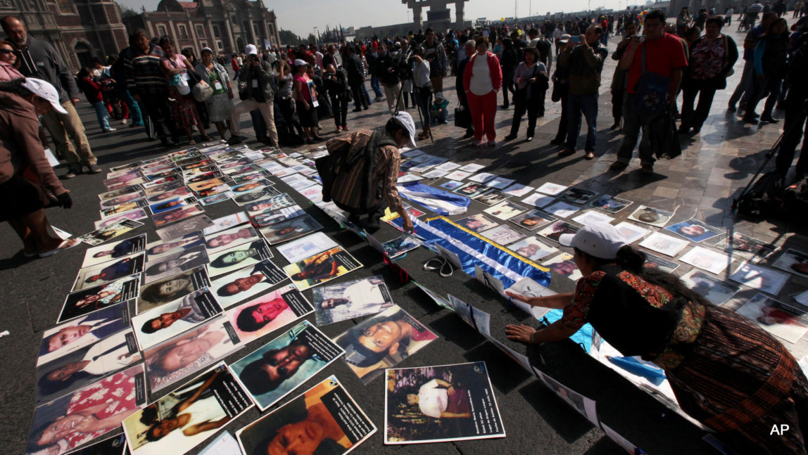 Central American mothers lay pictures of their children who went missing while crossing Mexico for the United States, on the steps of the Basilica de Guadalupe in Mexico City, Saturday Nov. 29, 2014.
