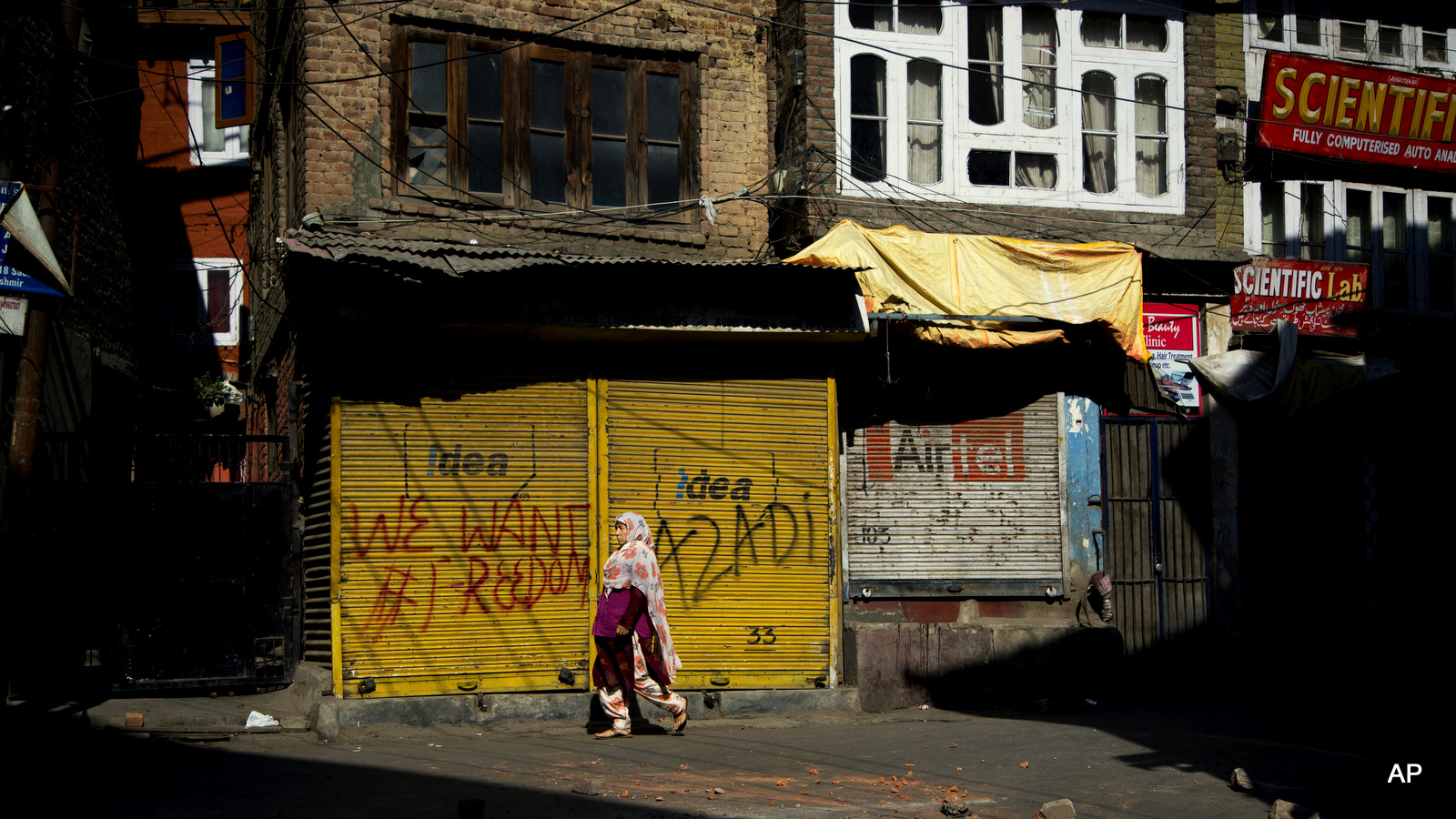 A Kashmiri woman walks on a road dotted with bricks and stones after a protest during curfew in Srinagar, Indian occupied Kashmir, Friday, Sept. 30, 2016.