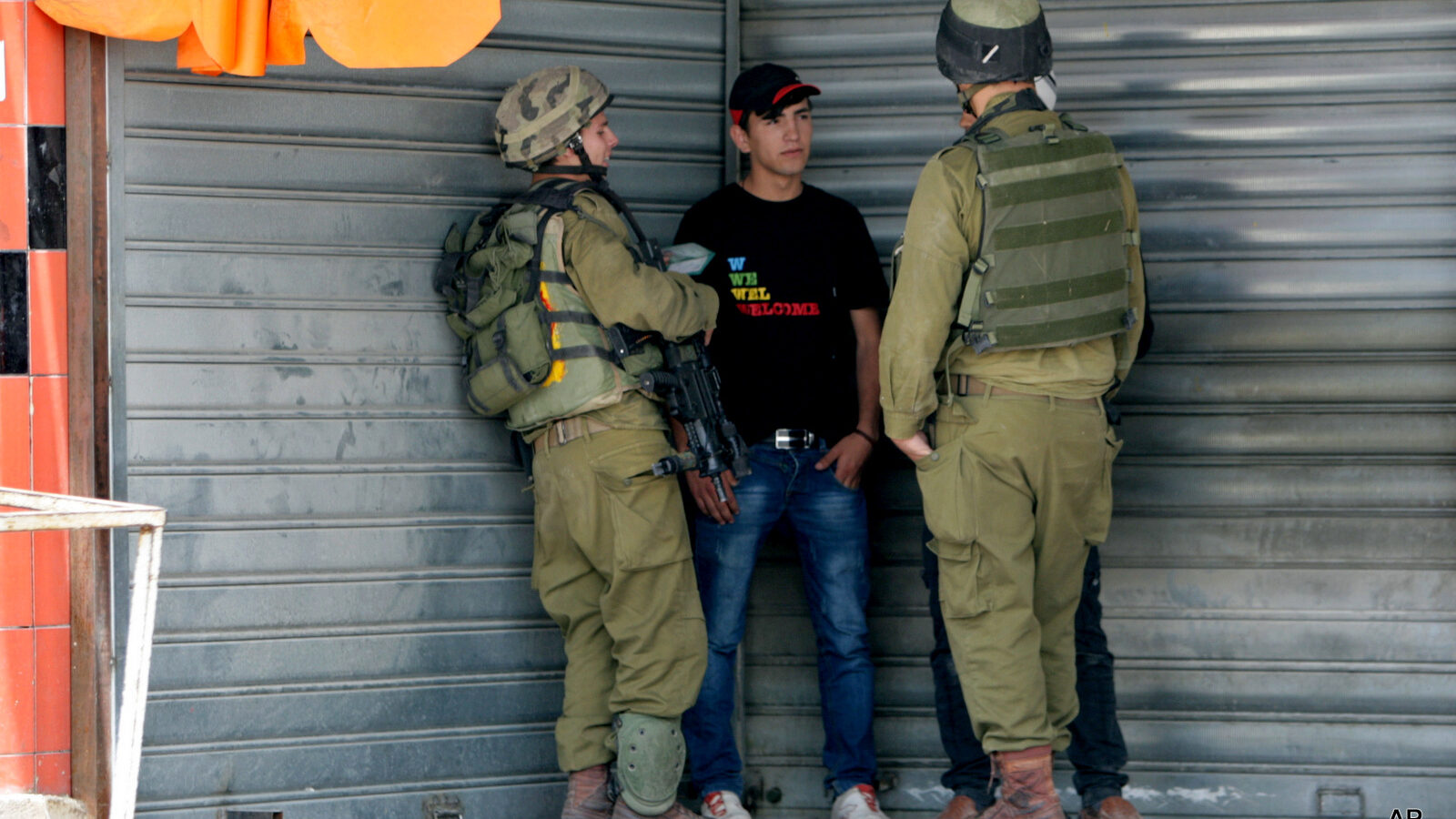 Israeli soldiers check the IDs of Palestinians near an Israeli checkpoint near Nablus, in the Israeli occupied West Bank, Tuesday, June 3, 2014.