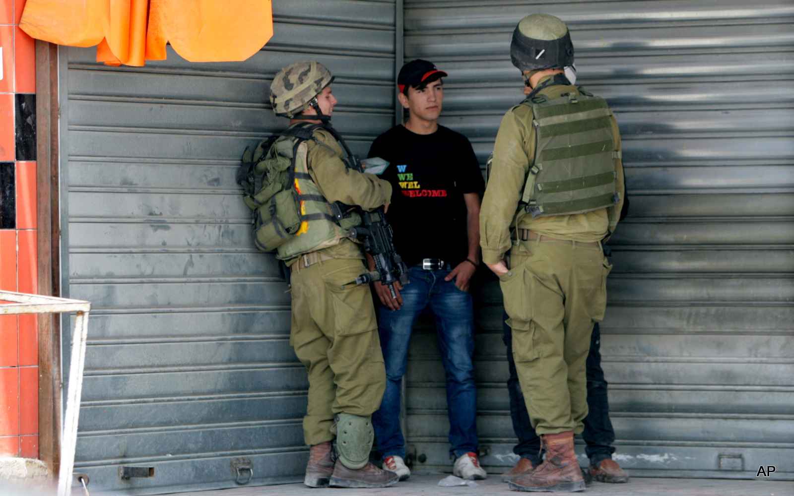 Israeli soldiers check the IDs of Palestinians near an Israeli checkpoint near Nablus, in the Israeli occupied West Bank, Tuesday, June 3, 2014.