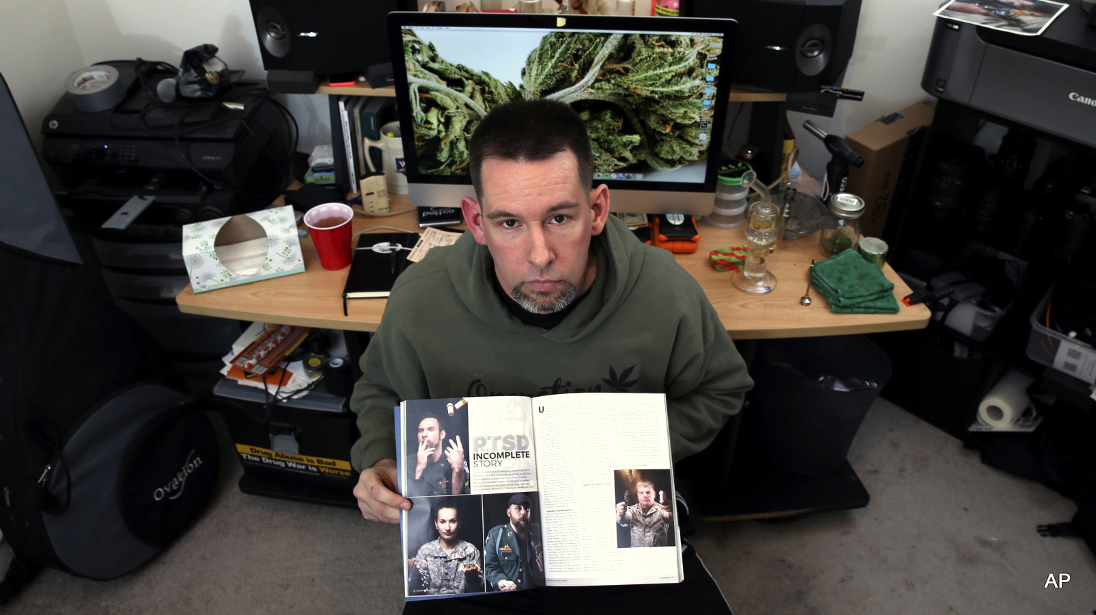 Former U.S. Marine Mike Whiter, who uses marijuana to treat post-traumatic stress disorder, displays some of his photographs of military personnel published in a magazine, as he sits at a desk in his home in Philadelphia. A growing number of states are weighing whether to legalize marijuana to treat PTSD.