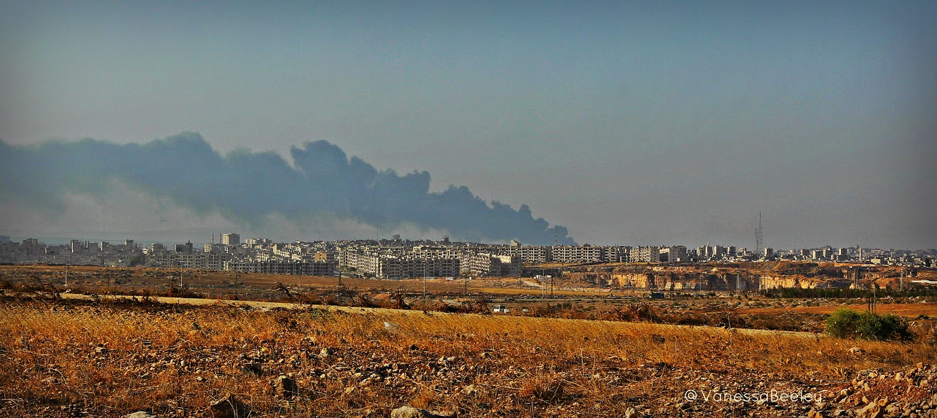 Ensimmäinen näkymä al-Ramouseh, esikaupungissa Kaakkois Aleppo.  Savu on peräisin palavasta Tarwell jälkeen pommitettiin terroristit kolme tai neljä päivää ennen.  (Kuva Vanessa Beeley)