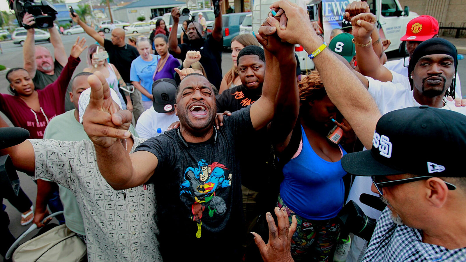 Pastor Russell Bowman, center, prays out loud as people gather at the scene where an African-American man was shot by police in El Cajon, east of San Diego, Calif., Tuesday, Sept. 27, 2016.