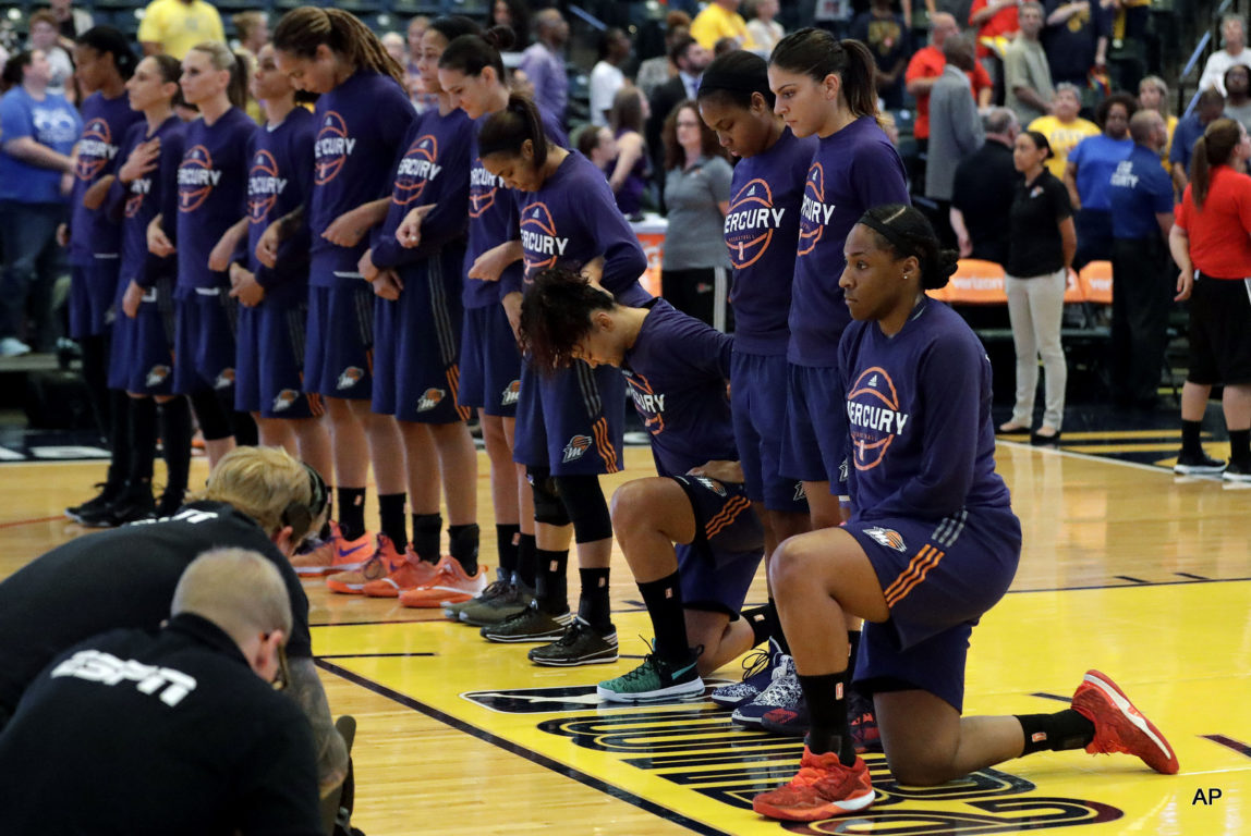 This Sept. 21, 2016, file photo shows, Phoenix Mercury's Kelsey Bone, right, and Mistie Bass, second from right, kneeling during the playing of the national anthem before the start of a first round WNBA playoff basketball game a in Indianapolis.
